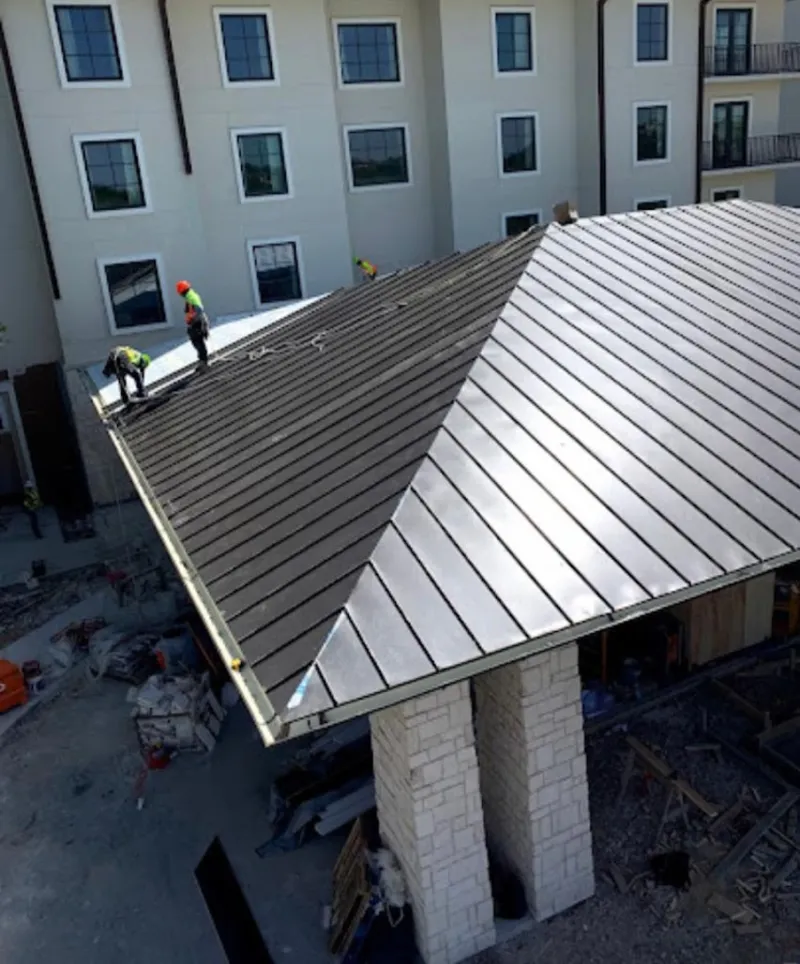 Crew installing standing seam metal roof panels on a commercial project in Edgewater